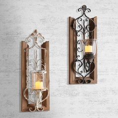 two wall sconces with candles in them hanging on a white wall next to each other