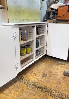 a kitchen with white cabinets and wood flooring on the ground next to an open refrigerator