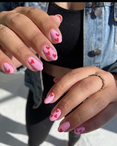 a woman's hands with pink and red hearts painted on them, holding onto her nails