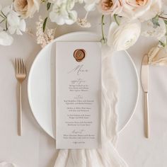 a white plate with a menu on it next to some silverware and pink flowers