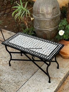 a black and white table sitting on top of a stone floor next to potted plants