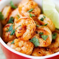 a red bowl filled with shrimp and garnished with cilantro