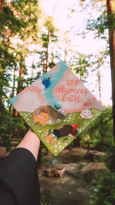 someone is holding up their graduation cap in the woods