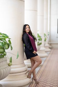 a beautiful young woman leaning against a pillar