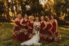 a group of women standing next to each other wearing red dresses and holding wreaths