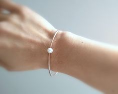 Simple, timeless, clean and beautiful! This pearl cuff bracelet is simply gorgeous. Each pearl is hand-drilled and sits very pretty along the top of this minimalist design. You can choose from 14kt gold fill, 14kt rose gold fill or sterling silver. Each genuine pearl is approximately 6mm in diameter. You can select from small, medium and large according to your wrist size. Your bracelet will arrive in a gift box with bow. White Jubilee Cuff Bracelet For Wedding, Rose Gold Jubilee Cuff Bracelet For Wedding, Rose Gold Jubilee Bracelet For Wedding, Dainty Jubilee Bracelet Bangle For Wedding, Classic Wedding Bangle With Oyster Bracelet, Minimalist Rose Gold Bracelets For Wedding, Classic White Cuff Bracelet For Wedding, Minimalist Round Cuff Bracelet For Weddings, Minimalist Bangle Bracelets For Wedding