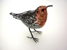 a wire bird sitting on top of a white surface