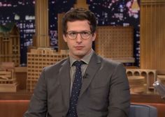 a man wearing glasses and a suit sitting in front of a microphone on the tonight show