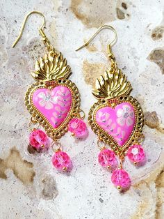 Beautiful and modern hand painted sacred heart earrings, in fuchsia pink, with pink light and silver flowers, adorned with pink glass stones. These earrings are painted in detail and look really beautiful, they are finished with high quality jewelry varnish to protect the paint. These hand painted sacred heart earrings are unique and very beautiful, the ideal gift because they match any outfit both day and night, they will enhance your beauty and you will surely attract attention due to the unique and handcrafted design, the ideal gift for holidays or simply to make that special person happy. Features/ Product info Note: The earrings in stock have some differences because they are hand painted. -The Main Material: Brass -Color: Fuchsia pink -Small: 1 in  (Please see the photos, this design Sacred Heart Art, Mexican Earrings, Ethiopian Opal Ring, Enhance Your Beauty, Color Fuchsia, Hypoallergenic Jewelry, Funky Jewelry, Fuchsia Pink, Heart Art