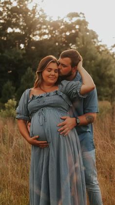 a pregnant couple hugging and smiling for the camera