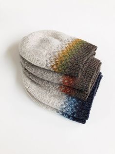 three knitted hats are stacked on top of each other, one is multicolored