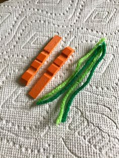 two pieces of orange and green string sitting on top of a white cloth covered table