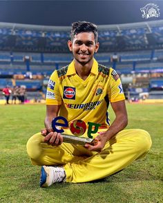 a man sitting on top of a field holding a trophy