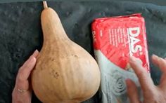 a person holding a wooden object next to a bag of potato chips and a pear