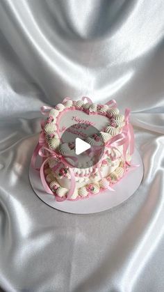 a heart shaped cake sitting on top of a white table covered in pink and white frosting