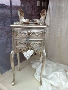 a silver dresser with shoes on it in front of a window