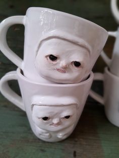 three white coffee cups with faces on them