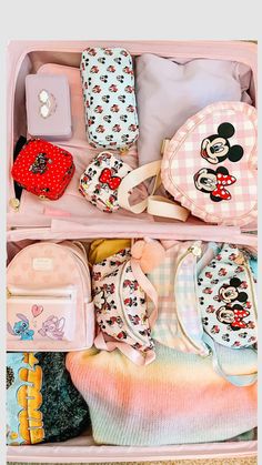 an open pink suitcase filled with lots of baby clothes and accessories on top of a carpeted floor