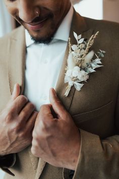 a close up of a person wearing a suit and tie with flowers on the lapel