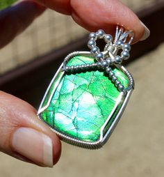 "WOW!!  This is a Very High Quality, Sparkling Dragon Skin Ammolite Fossil Pendant!  Ammolite is a rare, gem quality iridescent material cut from fossilized shells of extinct Ammolites, ancient sea creatures.  This particular Ammolite is only found in Alberta, Canada and is considered rarer than diamonds.  This Ammolite is a Very High Quality Stone and is known as a  \"Dragon Skin\" because of the pattern on the Fossil.  I purchased this Ammollite directly from the owners of the only mine in Canada and they only sell the BEST!  This Ammolite is a Fantastic, Bright Iridescent Emerald Green, Apple Green, Blue and Aqua Blue.  The Aqua Blue can also look a little Purple indoors turned at just the right angle.  This Ammolite is such an intense Emerald Green you are not going to be able to take Iridescent Fusion Gemstone Jewelry, Iridescent Fusion Style Gemstone Jewelry, Iridescent Fusion Style Jewelry With Gemstone, Handmade Iridescent Pendant Jewelry, Iridescent Jewelry With Natural Inclusions For Gift, Gift Jewelry With Iridescent Natural Inclusions, Iridescent Gemstone Jewelry For Jewelry Making, Artisan Iridescent Gemstone Jewelry, Iridescent Cabochon Jewelry Gift