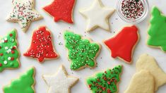 christmas cookies decorated with icing and sprinkles on a white tablecloth