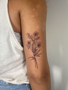 a woman with a tattoo on her arm holding a bouquet of wildflowers in it's left arm