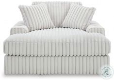 a white corded couch with two pillows on it's back and one arm