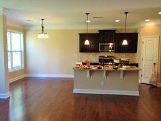 an empty kitchen and living room with hard wood flooring in the middle of it