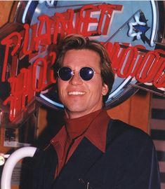 a man wearing sunglasses standing in front of a sign