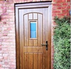 a close up of a wooden door on a brick building with bushes and shrubs in the background