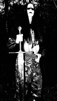 a woman dressed up as a demon holding a knife and fork in her hand, with trees in the background