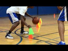 two young men playing basketball on an indoor court with cones in the foreground and one holding a ball