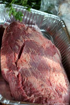 a piece of meat sitting on top of a metal pan next to some parsley