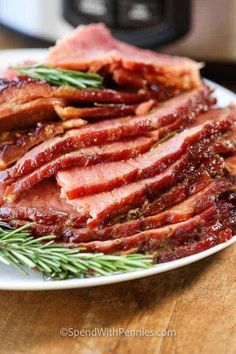 sliced ham on a plate with rosemary sprigs and an instant pressure cooker in the background