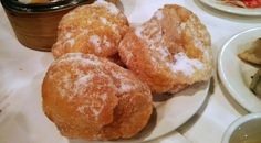 three sugar covered doughnuts on a plate next to bowls of soup and vegetables