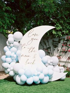 a white and blue balloon arch with an i love you to the moon and back sign