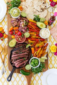 a platter with steak, vegetables and tortillas on it