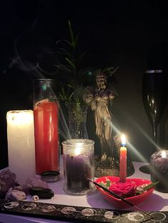 candles and other items on a table in front of a candle holder with an angel statue