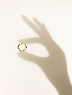 the shadow of a hand with a ring on it's left side, against a white background