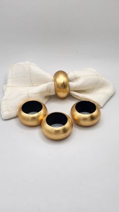 four gold rings are sitting on a white cloth with a bow tie around it's neck