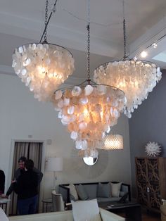 a chandelier made out of shells hangs from the ceiling in a living room