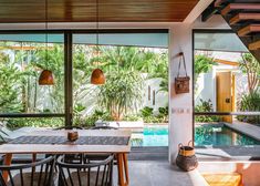 an outdoor dining area with wooden tables and chairs next to a swimming pool in the background