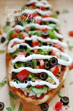 a long sandwich with olives, tomatoes, lettuce and black olives