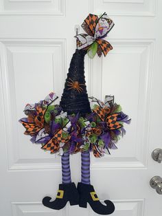 a door hanger decorated with halloween decorations and witch legs, hanging on the front door