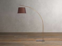 a floor lamp with a brown shade on the base and a white wall in the background