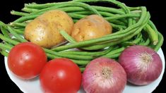 some green beans tomatoes and onions on a white plate