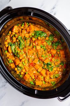 a crock pot filled with chickpeas and spinach in a curry sauce