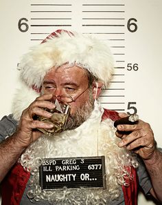 a man dressed as santa claus drinking from a glass in front of a christmas mug