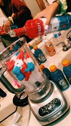 someone pouring something into a blender on top of a kitchen counter with other items