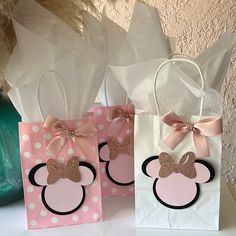 three bags with minnie mouse ears on them are sitting on a table next to a vase